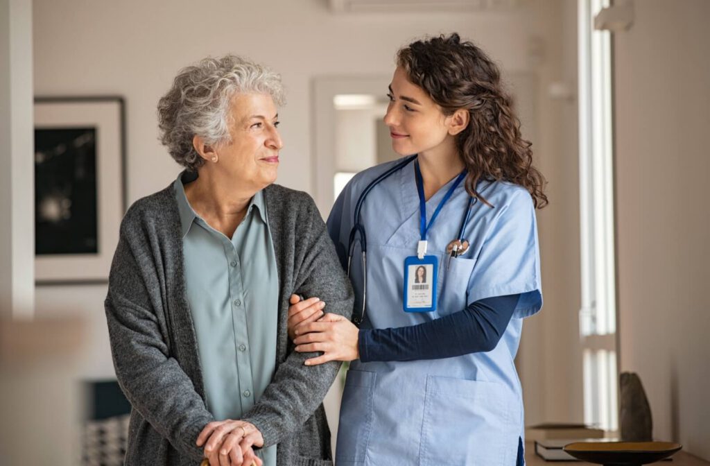 A senior at a memory care community walking with their care nurse