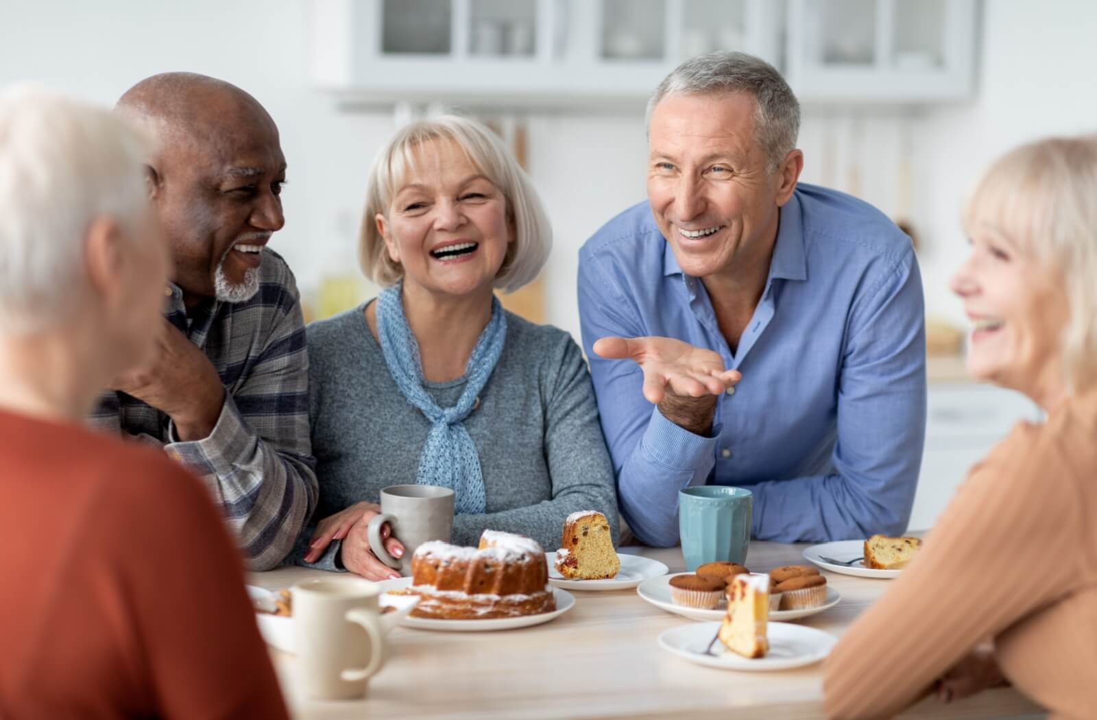 A group of seniors enjoying a cake together while they chat with friends at a senior living community