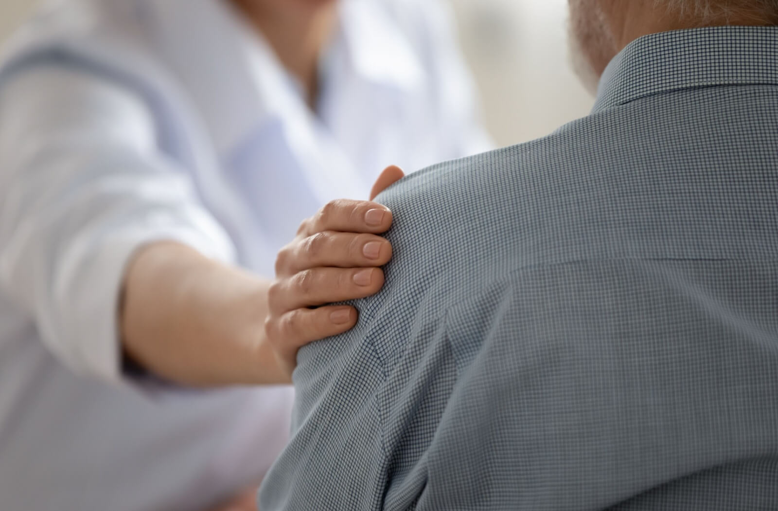 A close-up image of a healthcare professional reassuring an older adult after a dementia diagnosis.