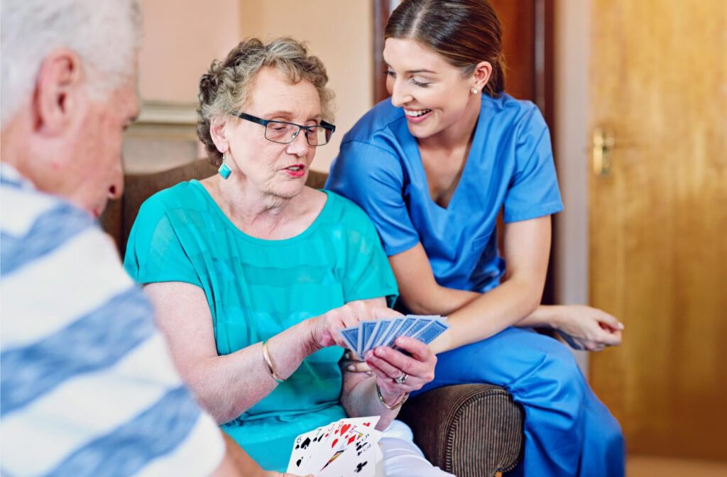 A caregiver checking on on a group of residents during a card game in the common area of assisted living.