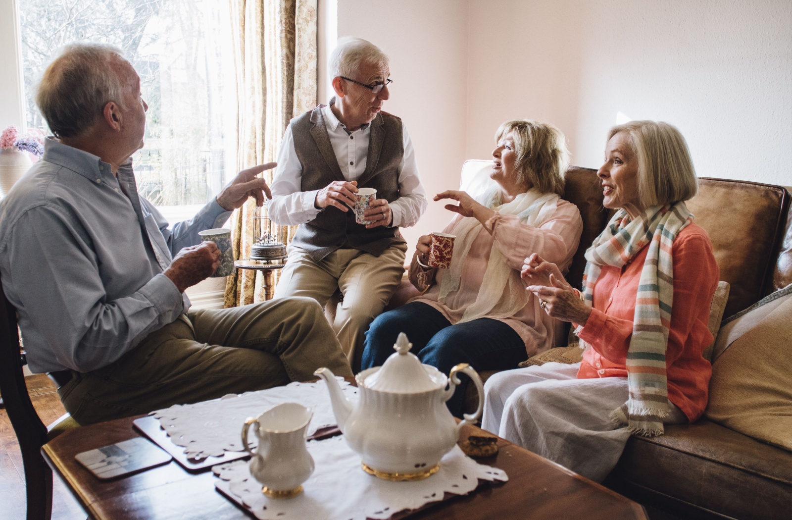 Four seniors chat and enjoy each other’s company over afternoon tea in a common space of their assisted living home